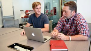 David Lee Kincheloe, a senior business administration major in the Poole College of Management, works on a client project in the Entrepreneurship Clinic with Lewis Sheats, director of the clinic.
